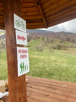 a sign on a wooden post with a sign on a building at Kuca za odmor ,,Balkan” in Crni Vrh