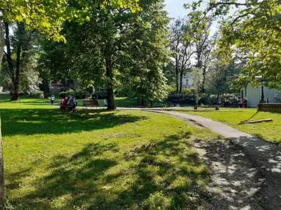 a path in a park with people sitting on a bench at Anilux studio in Vrnjačka Banja