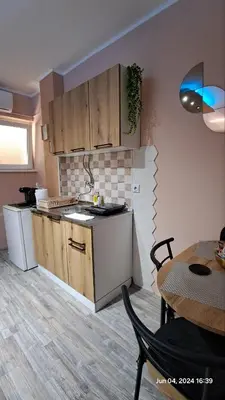 a kitchen with wooden cabinets and a table in a room at Apartman Iva in Zaječar