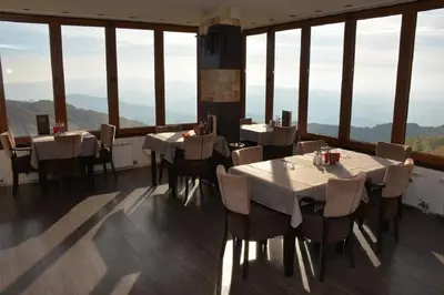 a dining room with tables and chairs and large windows at Pčelica L15 Milmari in Kopaonik