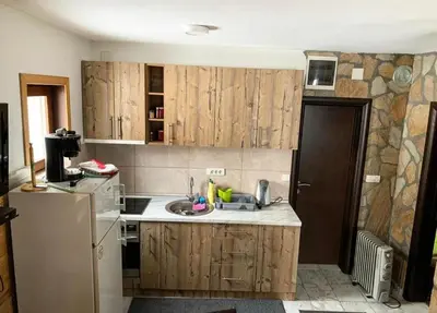 a kitchen with wooden cabinets and a white refrigerator at Apartman Tanja in Kopaonik