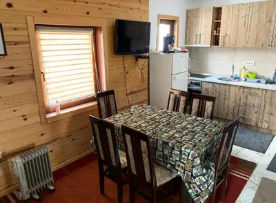 a kitchen with a table and chairs and a kitchen with a refrigerator at Apartman Tanja in Kopaonik