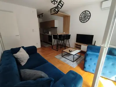 a living room with a blue couch and a television at Cvetkovic LUX Аpartmani & Free GARAŽA in Vrnjačka Banja