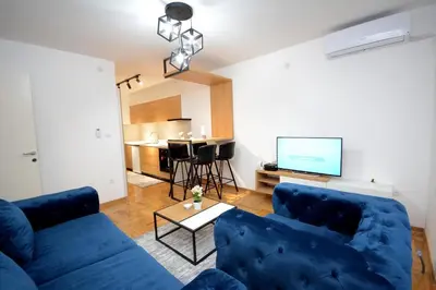 a living room with a blue couch and a tv at Cvetkovic LUX Аpartmani & Free GARAŽA in Vrnjačka Banja