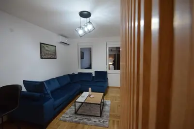 a living room with a blue couch and a table at Cvetkovic LUX Аpartmani & Free GARAŽA in Vrnjačka Banja