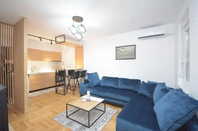 a living room with a blue couch and a table at Cvetkovic LUX Аpartmani & Free GARAŽA in Vrnjačka Banja