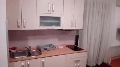 a kitchen with white cabinets and a sink and a microwave at FEEL LIKE HOME in Vrnjačka Banja