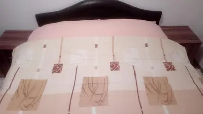 a bed with a brown and white comforter on it at FEEL LIKE HOME in Vrnjačka Banja