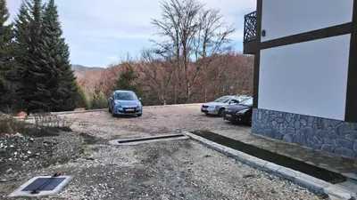 two cars parked in a parking lot next to a building at Top Kop in Kopaonik