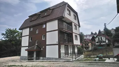 a white and brown house with a black roof at Top Kop in Kopaonik
