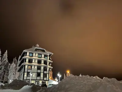 a building is covered in snow at night at VILA JEZERO in Kopaonik
