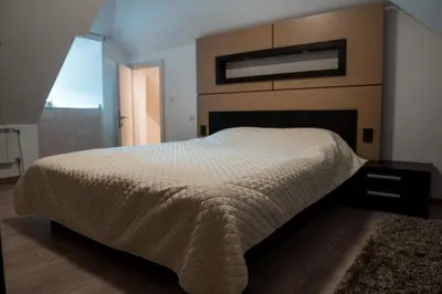 a bedroom with a large bed with a wooden headboard at VILA JEZERO in Kopaonik