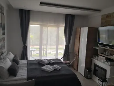a bedroom with a bed with a television and a balcony at Lux Suite S5 Milmari Resort in Kopaonik