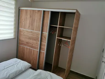 a closet with a wooden door next to a bed at Iznad oblaka A1 in Kopaonik