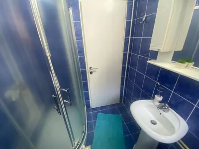 a blue tiled bathroom with a sink and a shower at Apartment 