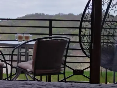a table and chair on a balcony with a view at Apartment Deluxe Sunny Valley Milmari S8 in Kopaonik