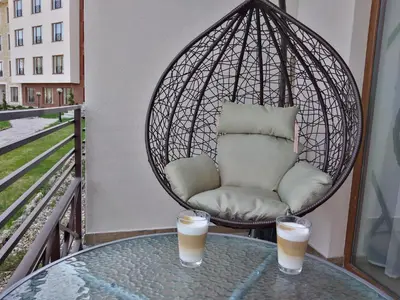 a swing chair on a balcony with two drinks on a table at Apartment Deluxe Sunny Valley Milmari S8 in Kopaonik