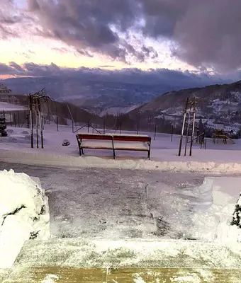 a bench sitting in the snow next to a body of water at Milmari P39 Kopaonik in Kopaonik