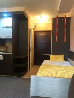 a bedroom with a large bed and a kitchen at Apartman VR46 in Kopaonik