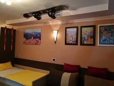 a room with a couch and pictures on the wall at Apartman VR46 in Kopaonik