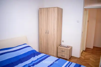 a bedroom with a bed and a wooden cabinet at Dusko dugousko in Niš