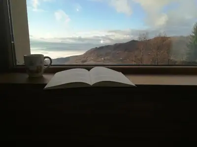 an open book sitting on a window sill with a coffee cup at Apartman D&V Milmari Resort S10 in Kopaonik