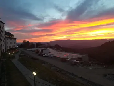 a sunset over a street with a building and cars at Apartman D&V Milmari Resort S10 in Kopaonik