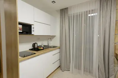 a kitchen with white cabinets and a counter top at Harmonija Resort - Harmonija Kopaonik in Kopaonik