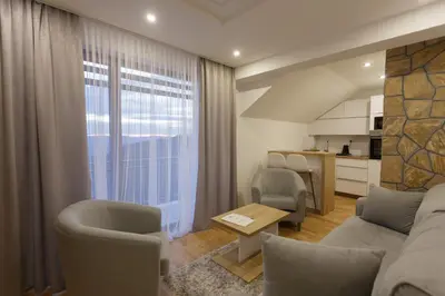 a living room with a couch and chairs and a kitchen at Harmonija Resort - Harmonija Kopaonik in Kopaonik