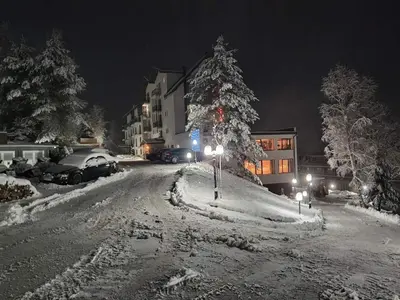 a snow covered street at night with a christmas tree at Harmonija Resort - Harmonija Kopaonik in Kopaonik