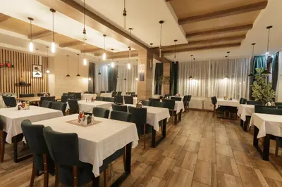 a dining room with white tables and chairs at Harmonija Resort - Harmonija Kopaonik in Kopaonik