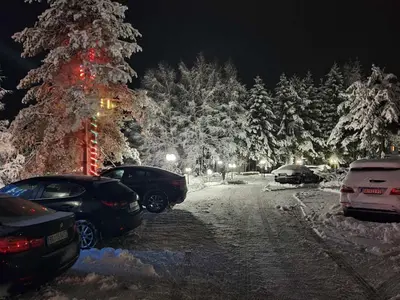 a snowy street with cars parked next to a christmas tree at Harmonija Resort - Harmonija Kopaonik in Kopaonik