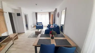 a living room with a table and blue chairs at Panorama Apartman - Milmari L47 in Kopaonik