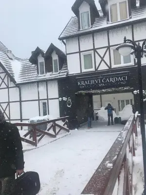 a man standing outside of a building in the snow at Kopaonik apartmani u Kraljevim Čardacima , Čar 27 i 6-13 in Kopaonik