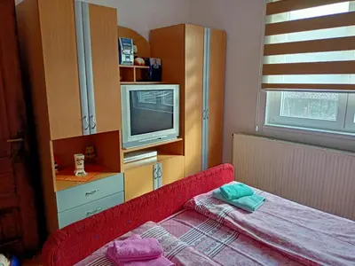 a small room with a television and a red couch at Kuca za odmor RADMILA - Rogljevacke pivnice in Rogljevo