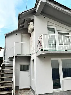 a white house with a staircase and a balcony at Apartman Sava in Niš