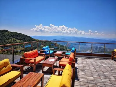 a balcony with chairs and tables and a view of the mountains at Milmari S30 in Kopaonik