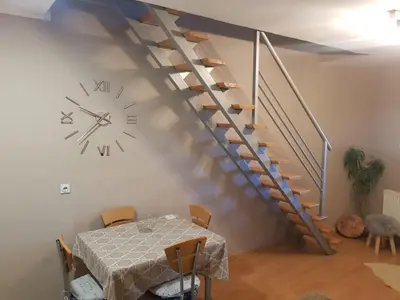 a dining room with a table and a clock and stairs at Košuta 21 Center Duplex Apartment, Brzeće in Brzeće