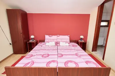 a large bed in a room with a red wall at Apartmani Stojadinović in Soko Banja
