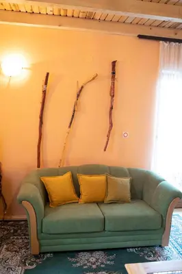 a green couch in a living room with logs on the wall at Apartment Luka-Lena in Kopaonik
