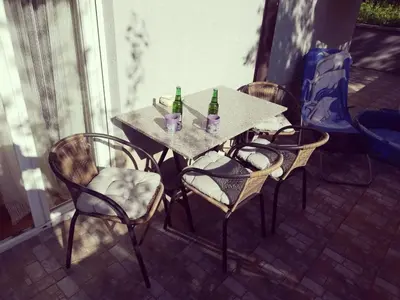 a table with three chairs and two bottles on it at PremiumPlus Apartman in Vrnjačka Banja