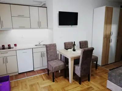 a kitchen with a table and chairs and a tv at PremiumPlus Apartman in Vrnjačka Banja