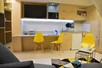 a kitchen with two yellow chairs and a kitchen counter at Family Lux Apartmani Angella Konaci in Kopaonik