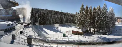 a snow covered slope with a building and trees at Family Lux Apartmani Angella Konaci in Kopaonik