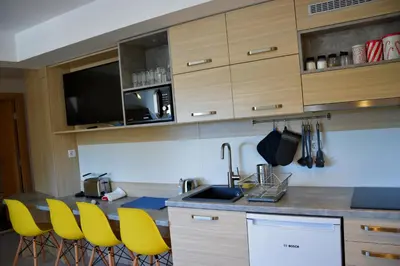 a kitchen with yellow chairs and a sink at Family Lux Apartmani Angella Konaci in Kopaonik
