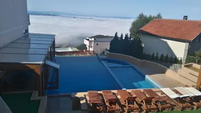 a swimming pool with chairs next to a building at Nana S44 Milmari Spa&Wellness in Kopaonik