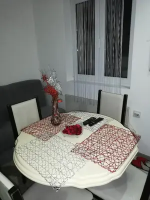 a dining room table with a vase of flowers on it at Andrina Sweet Home in Niš