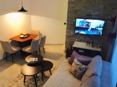 a living room with a couch and a tv on a brick wall at Apartman “EMI” in Kopaonik