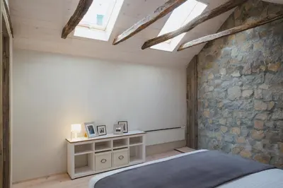 a bedroom with a bed and a stone wall at Kostovac Boutique Homes - Loft in Kopaonik
