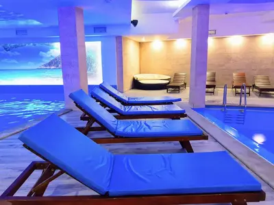 a pool with blue lounge chairs next to a swimming pool at Kopaonik Milmari Spa and Wellness Wooden Horn S21 in Kopaonik